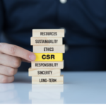 Una mano colocando piezas de madera con diferentes palabras REsources, Sustaninability, Ethics, Responsability, Sincerity, Long-Term y destacada en amarillo CSR