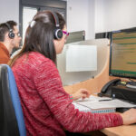 Varias personas sentadas en una sillas frente a un ordenador trabajando en el Call-Center de DFA