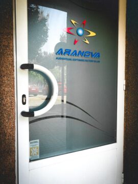 Puerta de las oficinas de ARANOVA con el sello del "Establecimiento Adherido al Arbitraje y Consumo del Gobierno de Aragón" en la parte inferiro izquierda de la puerta