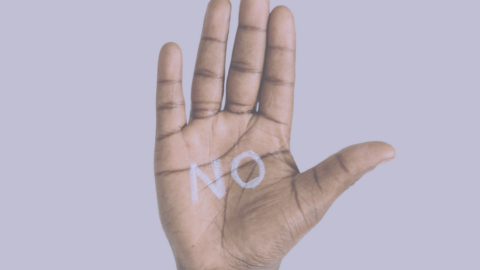 Mano delante de fondo violeta con un NO escrito en su palma