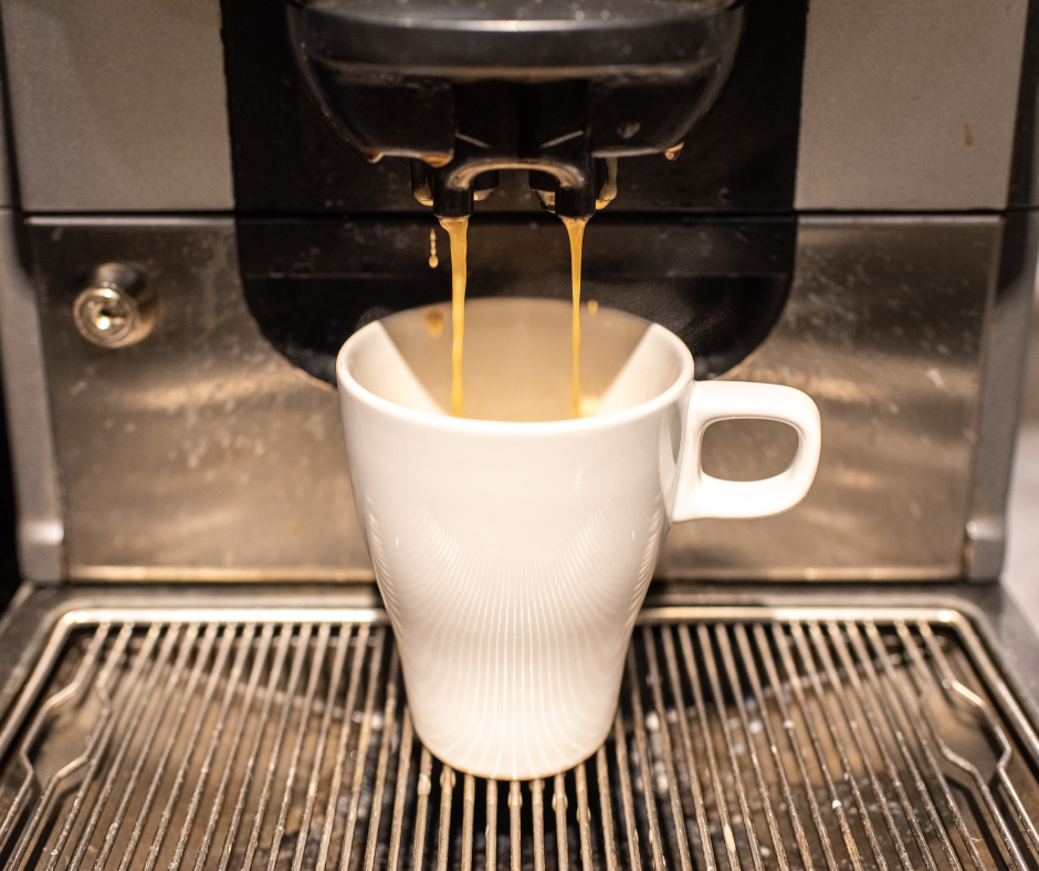Taza de café puesa en la máquia esperando a que se termine de hacer el café