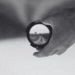 Imagen de una mano sujetando un objetivo de cámara de fotos enseñando el camino