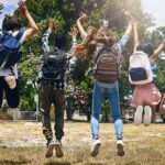 Niños saliendo del cole dando saltos de alegria antes de comenzar las vacaciones